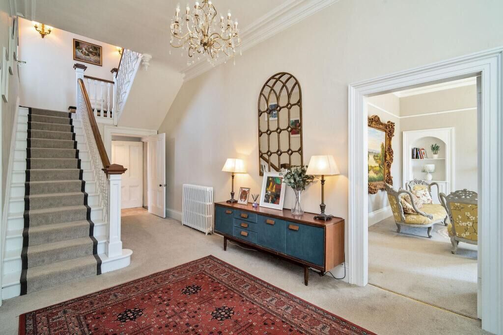 A staircase with a carpeted landing, a blue cabinet with lamps, and a red rug.