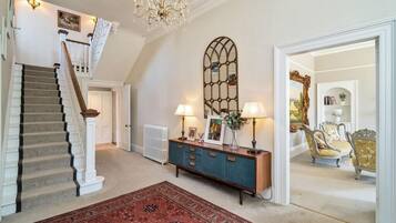 A staircase with a carpeted landing, a blue cabinet with lamps, and a red rug.