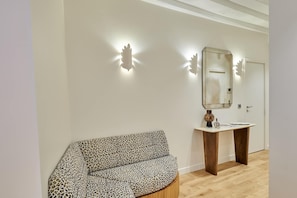 Ein Zimmer mit einem Leopardenmuster-Sessel, einem Holztischchen, einem Spiegel und einer Tür.
