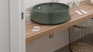 A bathroom with a round mirror, a green sink, and a wooden countertop. - Marezè (Santa Croce Camerina)