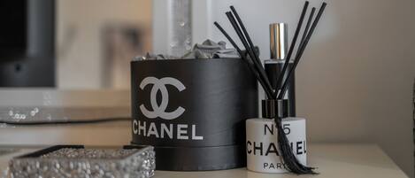 A black Chanel perfume box and a white Chanel perfume bottle on a reflective surface.