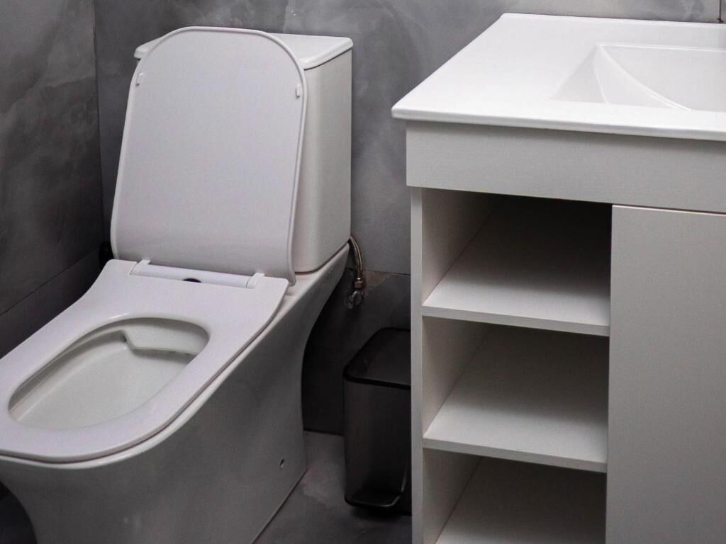 A modern bathroom with a toilet, a sink, and a trash bin.