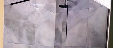 A modern shower with a glass door and a handheld showerhead.