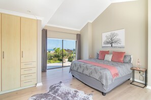 Een slaapkamer met een groot bed, een kledingkast, uitzicht op het omliggende landschap en een schilderij aan de muur.