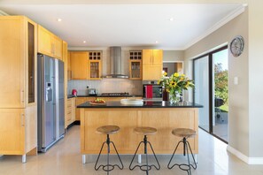 Een moderne keuken met houten kastjes, roestvrijstalen apparatuur en een centraal eiland met krukken.