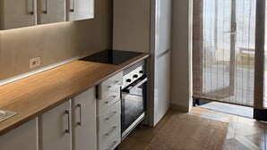 Et moderne køkken med indbygget ovn, et køleskab og et unikt loftlampe.
