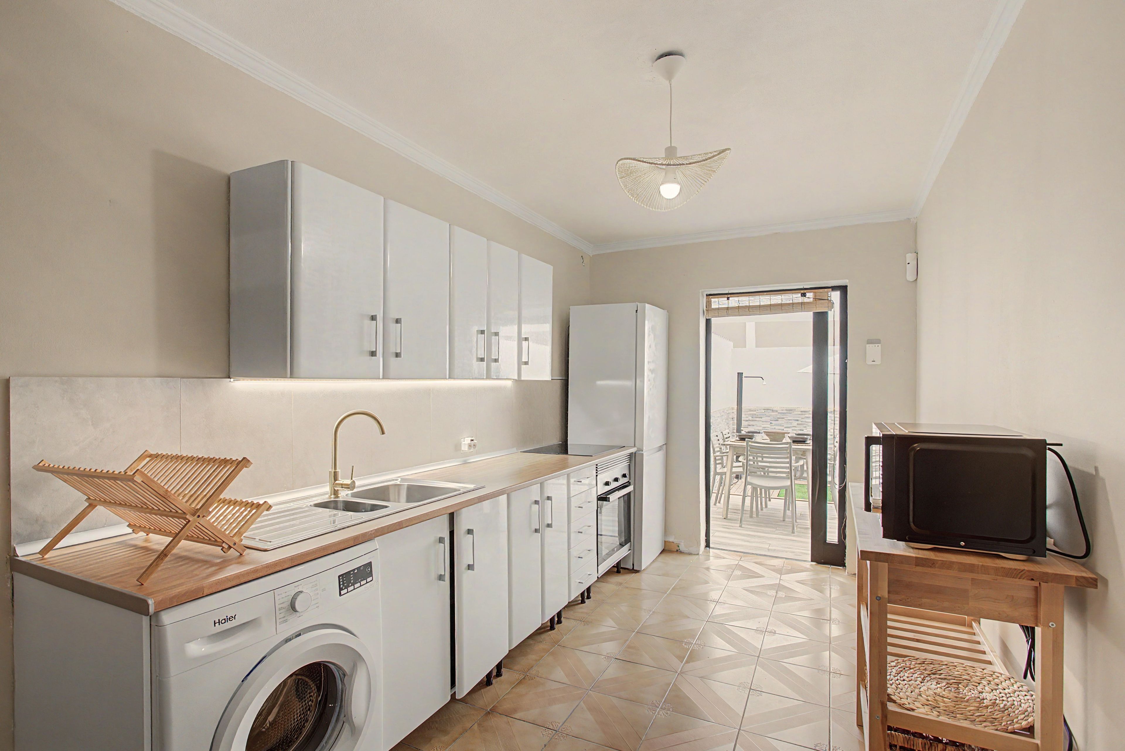 A compact kitchen with a washing machine, a sink, and cabinets.