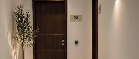 Ein Hotel Eingang mit einer Holztür, einem Blumentopf und einem Schild darüber.