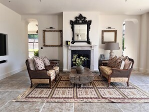 Una sala de estar con chimenea, dos sofás, una mesa de centro y una alfombra.