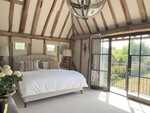 A bedroom with a large bed, a chandelier, a window, and a view of the outdoors.