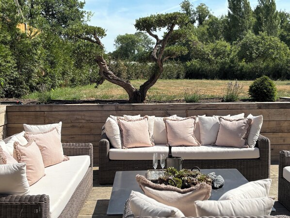 An outdoor seating area with a wicker sofa, cushions, and a coffee table with decorative items.