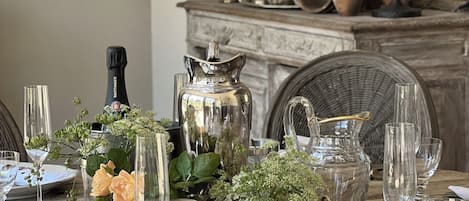A dining table set with glassware, a champagne bottle, and a decorative centerpiece.