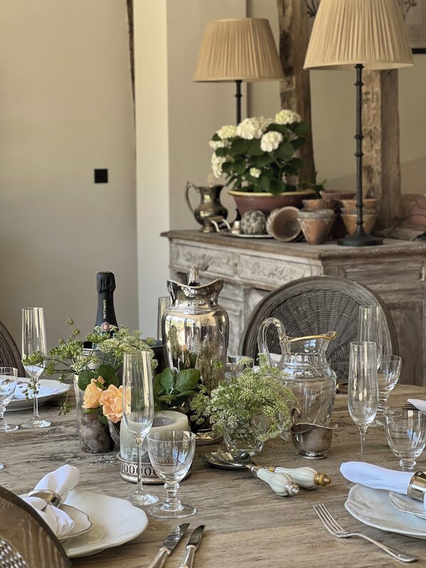 Une table à manger dressée avec de la verrerie, une bouteille de champagne et un centre de table décoratif.