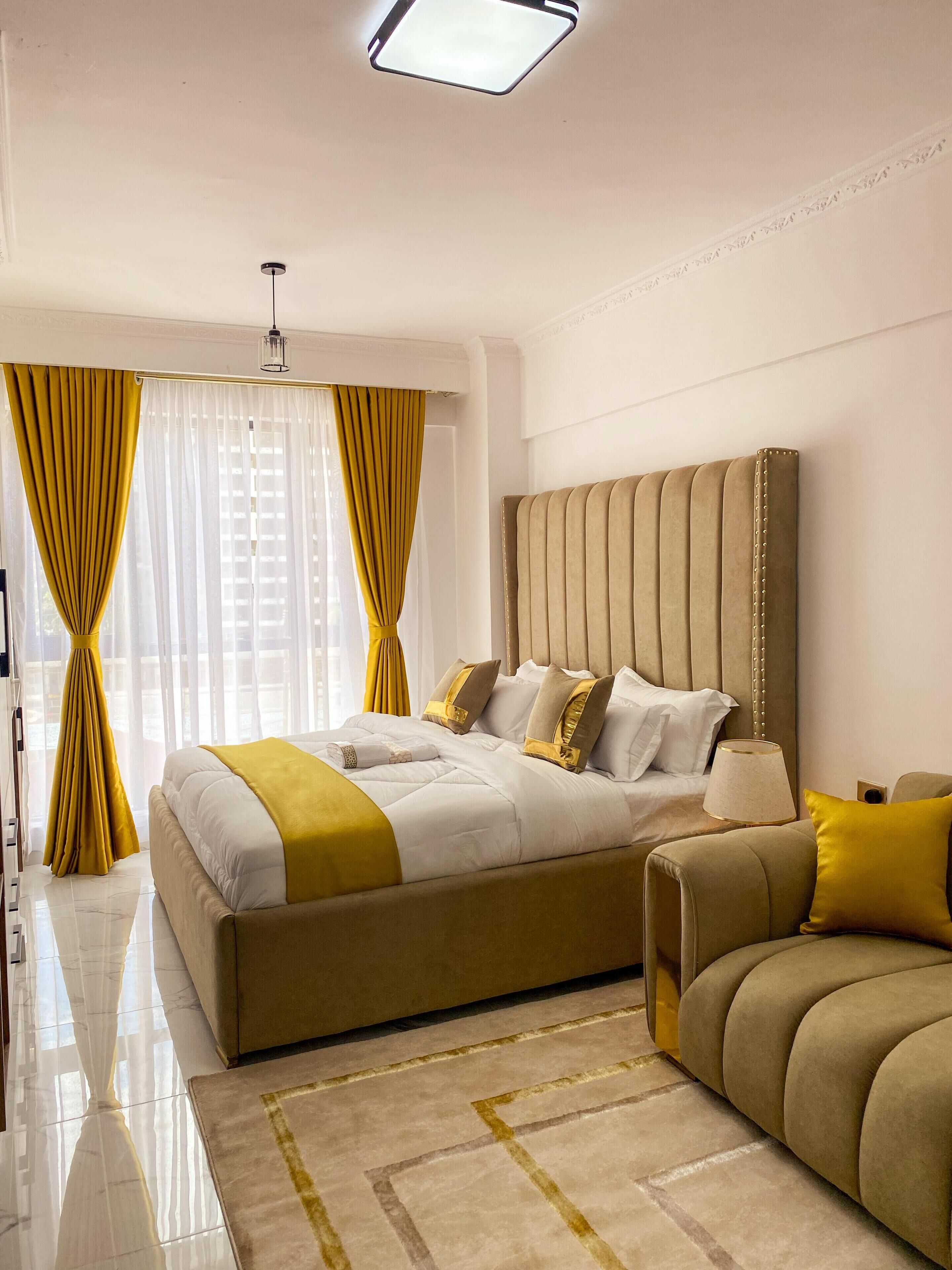 A modern bedroom with a large bed, a headboard with vertical lines, and a bedside table with a lamp.