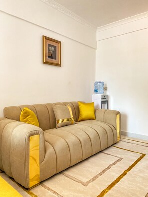 A beige sofa with yellow cushions, a framed picture on the wall, and a water dispenser in the corner. - Smart Homes View Palace Apartment (Nairobi)