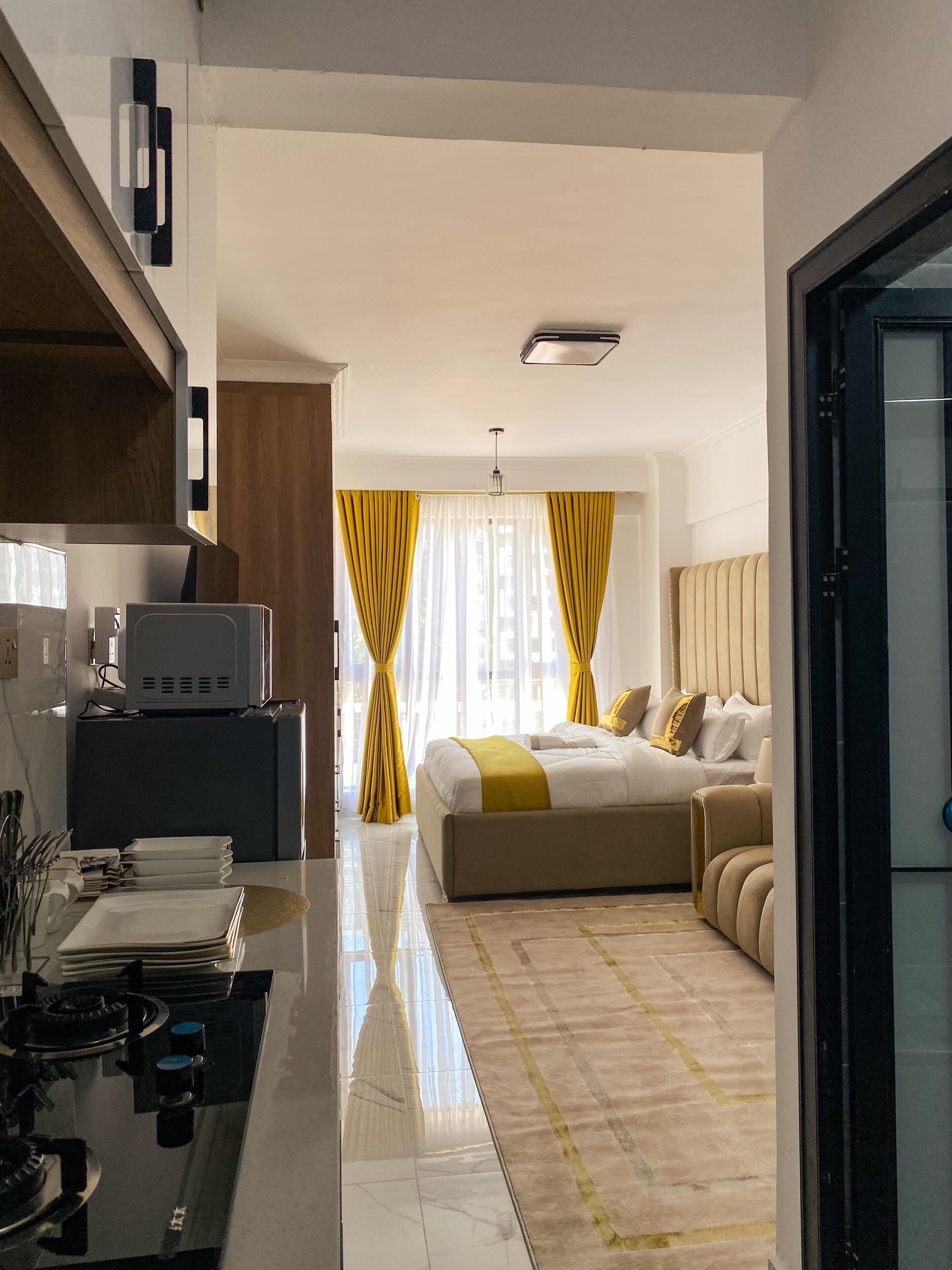 Et moderne hotelværelse med seng, skrivebord med computer og et tekøkken.