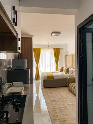 Habitació d'hotel moderna amb llit, escriptori amb ordinador i zona de cuina.
