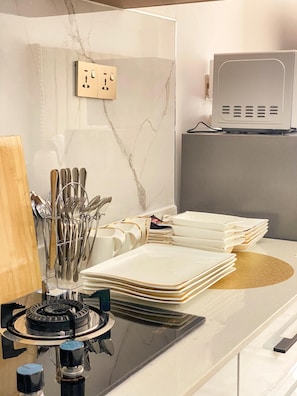 A kitchen counter with a gas stove, a set of knives, and a stack of white plates. - Smart Homes View Palace Apartment (Nairobi)