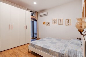 A bedroom with a bed, wardrobe, and air conditioning unit. - GuestHost - Iglesias Modern Apartment (sleeps 4) (Iglesias)