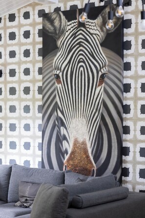 Ein Zebra-Gemälde an einer Wand mit geometrisch gemustertem Tapeten.