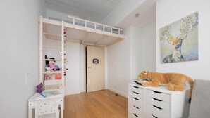 Une chambre d’enfant avec un lit superposé, un bureau avec une chaise et un grand tableau accroché au mur.