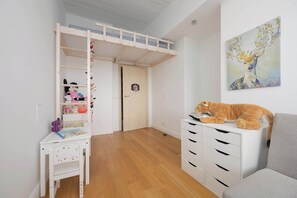 Ein Kinderzimmer mit Etagenbett, Schreibtisch und Stuhl sowie einem großen Gemälde an der Wand.