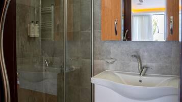 Een moderne badkamer met een douchecabine van glas, een witte wastafel met één kraan en houten kasten.