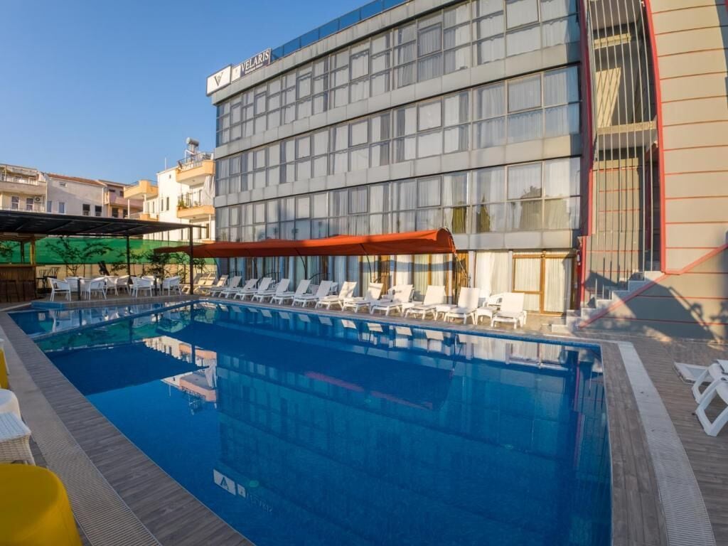 A swimming pool with lounge chairs and a building with a sign.