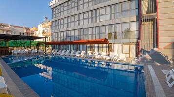 Una piscina con sillas de descanso y un edificio con un letrero.