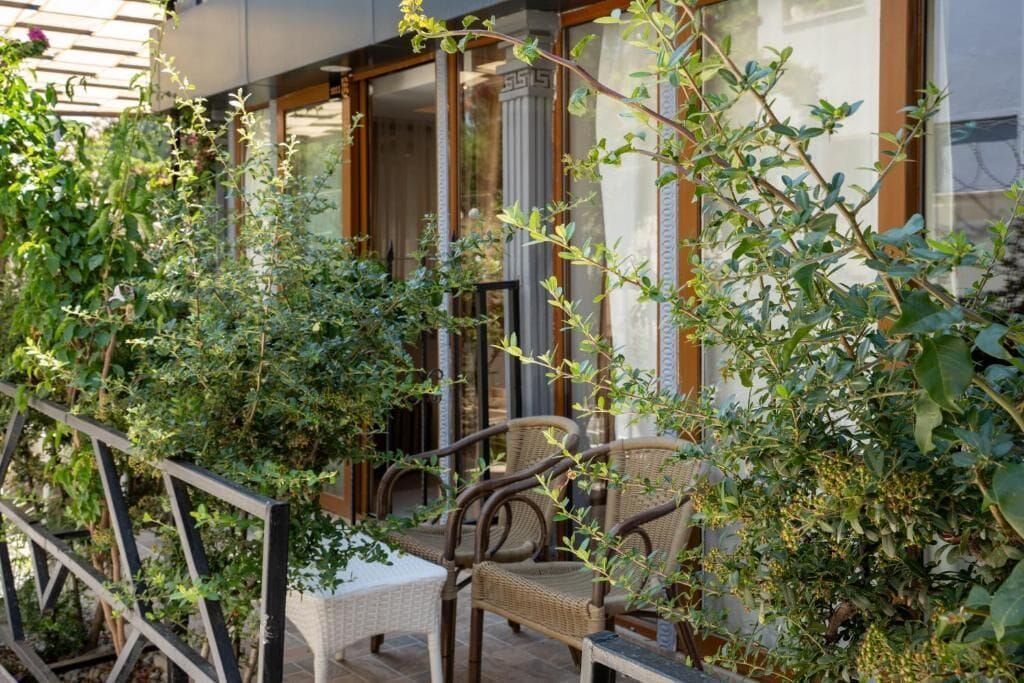 A balcony with wicker furniture and lush greenery.
