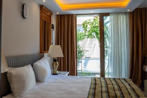 A hotel room with a bed, a nightstand, a lamp, and a view of the outdoors through a sliding door. - Velaris Boutique Hotel (Serik)