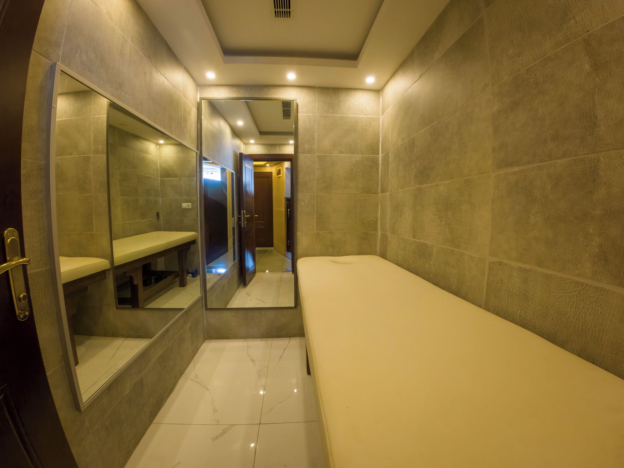 Un couloir étroit avec un banc, un miroir et une porte donnant sur une autre pièce.