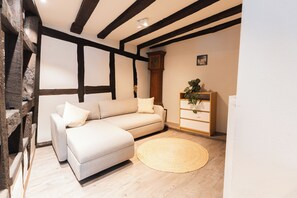 A room with a sofa, a wooden cabinet, and a round woven rug. - Burdengasse 1681 | Half-timbered house | 160 m² | Boppard Old Town | 8 guests (Boppard)