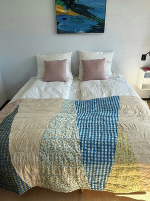 A bed with a quilt, two pillows, and a painting above it. - Undisturbed house at the foot of Mols Bjerge (Knebel)