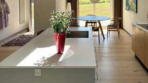 Moderni keittiö, jossa on keskeinen saareke, riippuvalaisimet ja näkymä ulos.