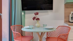 A dining area with a round table, two chairs, a vase with flowers, and a flat-screen TV mounted on the wall. - Granaria A105 | Terrace | Perfect for Couples (Gdańsk)