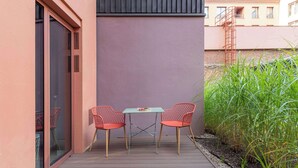 An outdoor patio with two red chairs and a table, a glass door, and a metal staircase. - Granaria A105 | Terrace | Perfect for Couples (Gdańsk)