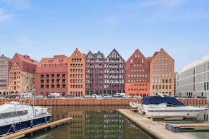 Ein Yachthafen mit vertäuten Booten, ein großes, rot gefärbtes Gebäude im modernen Stil und ein klarer Himmel.