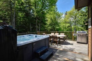 Eine Außenterrasse mit Whirlpool, Tisch, Stühlen und Grill.