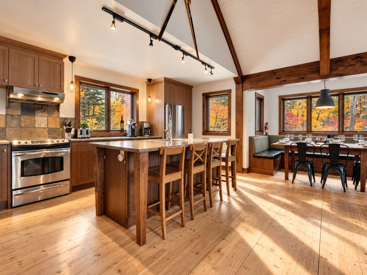 A spacious kitchen with a central island, wooden bar stools, and a dining area with a table and chairs.