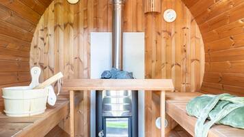 L'interno di una baita in legno con una sauna, un tavolo di legno e una panca.