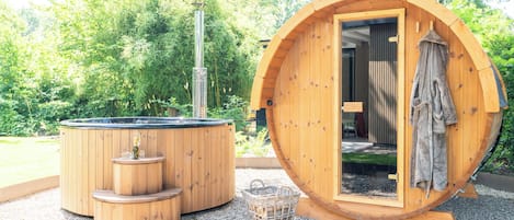 Un bain à remous en bois et un sauna, installés dans un cadre verdoyant.
