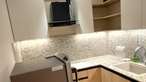 A compact kitchen with a built-in refrigerator, a sink, and a microwave.