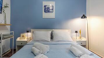 Una camera d'albergo con un letto, due comodini, una lampada, un'opera d'arte incorniciata e una piccola pianta.