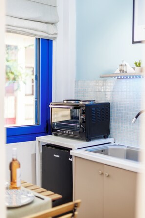 A compact kitchen with a built-in toaster oven, a sink, and a window with a blue frame.