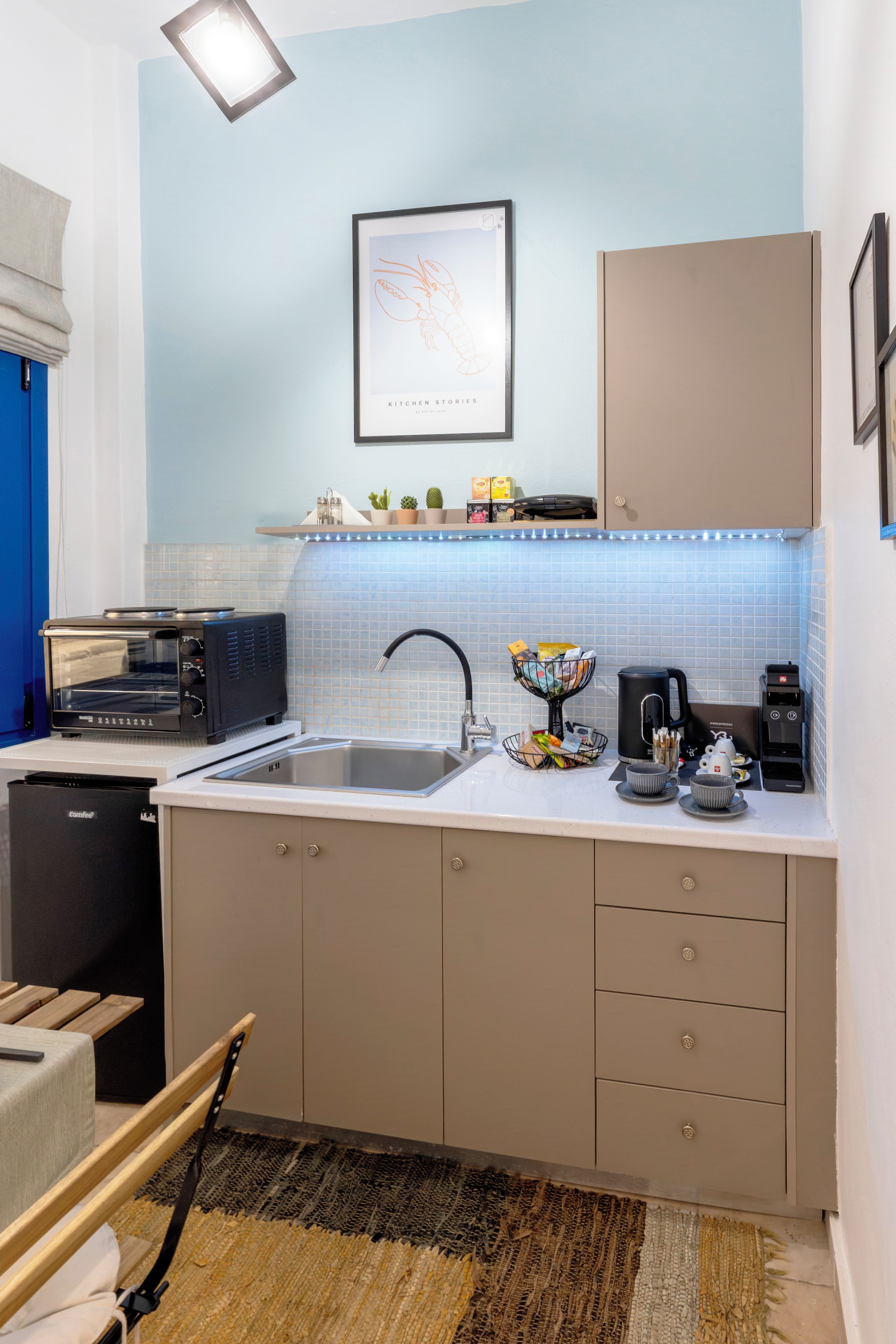 A compact kitchen with a sink, a coffee machine, a toaster, and a small refrigerator.