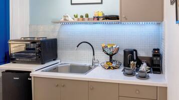 A compact kitchen with a sink, a coffee machine, a toaster, and a small refrigerator.