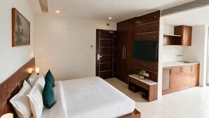 A modern hotel room with a bed, a desk, a TV, and a wardrobe. - Hotel Oasis One (Gurugram)