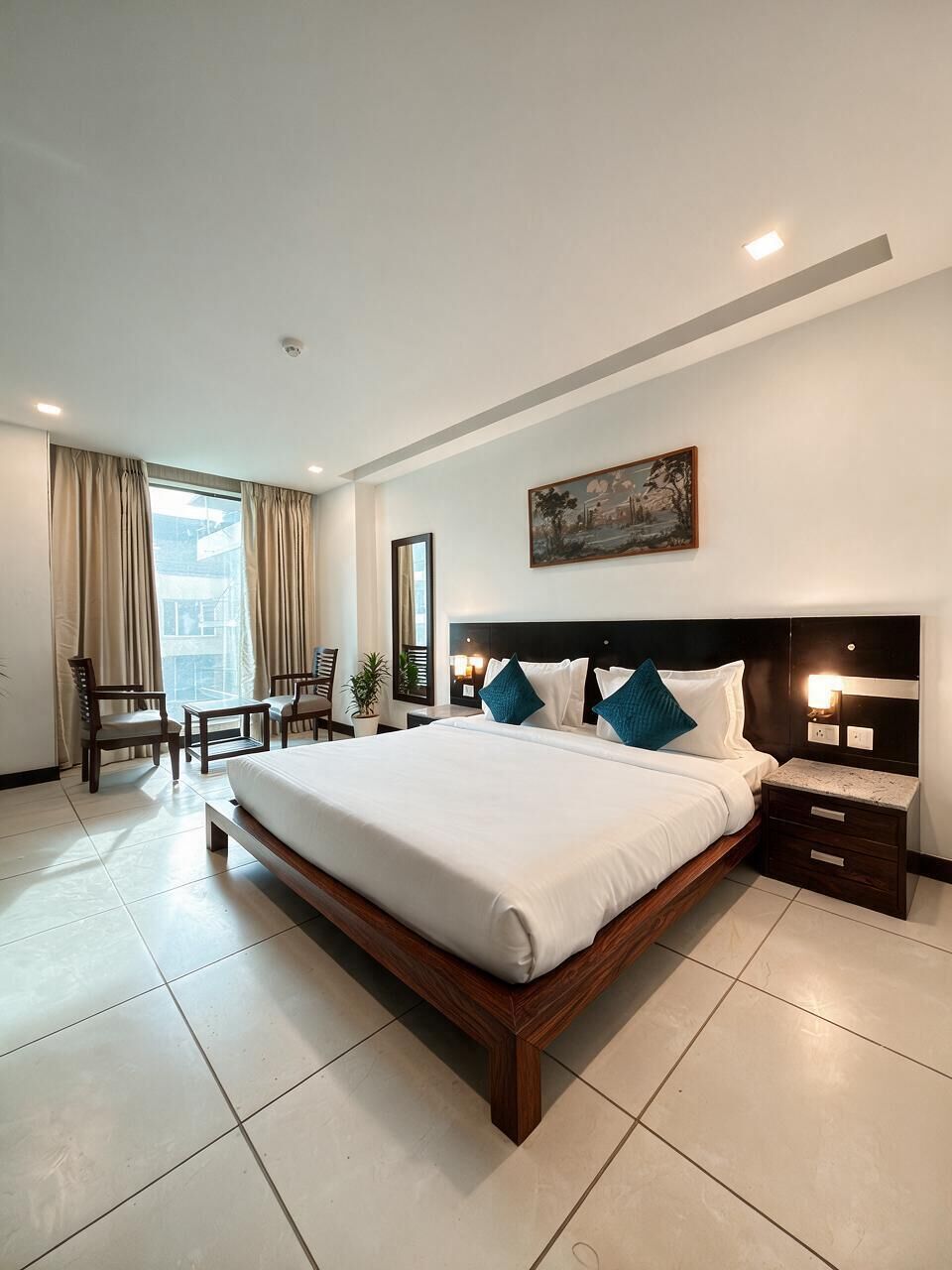 A hotel room with a large bed, bedside tables, a desk, and a chair.