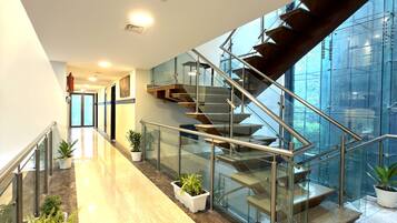 A modern interior with a glass staircase, marble flooring, and potted plants.